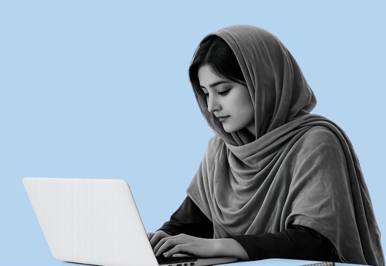 A young woman in a headscarf studying on a laptop
